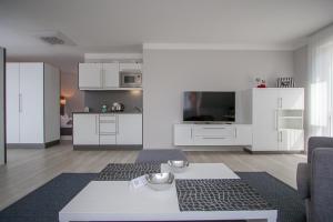 ein Wohnzimmer mit weißen Schränken und einem Tisch in der Unterkunft ApartHotel "Am Fließ" in Hoyerswerda
