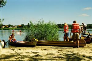 eine Gruppe von Menschen, die um Kanus am Strand stehen in der Unterkunft Silkeborg Sø Camping Apartments in Silkeborg