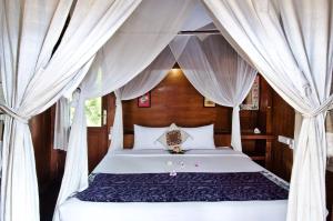a bedroom with a bed with white drapes at Lumbung Bali Huts in Nusa Lembongan