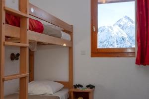a bedroom with bunk beds and a window with mountains at R&eacute;sidence Go&eacute;lia Les Balcons du Soleil in Les Deux Alpes