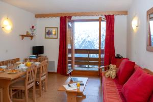 a living room with a red couch and a dining table at Résidence Goélia Les Balcons du Soleil in Les Deux Alpes