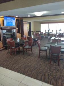 a dining room with tables and chairs and a television at Baymont by Wyndham Madison Heights Detroit Area in Madison Heights