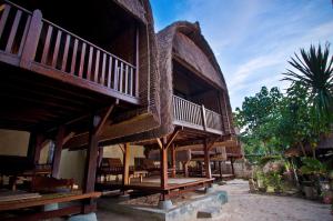 a large wooden building with a balcony and tables at Lumbung Bali Huts in Nusa Lembongan