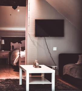 uma sala de estar com uma televisão e uma mesa branca em Hôtel L'etoile De Marie em Rocroi