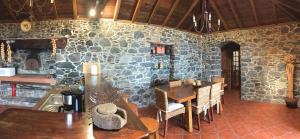 Habitación con mesa, sillas y pared de piedra. en Casa dos Reis, en Calheta