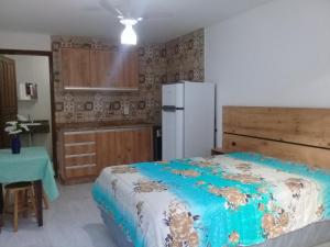 a kitchen with a bed and a refrigerator in a room at Pousada Maria Helena in Guaratuba