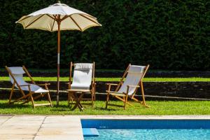 duas cadeiras e um guarda-sol ao lado de uma piscina em Liiiving in Caminha | Countryside Pool House em Caminha