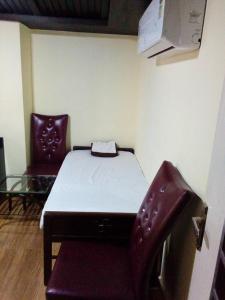 Habitación pequeña con cama y silla. en Hotel Anandhiram Heritage en kāraikāl