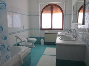 La salle de bains est pourvue de 2 lavabos, de toilettes et d'une baignoire. dans l'établissement L'Ambra, à Alghero