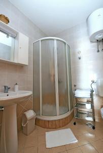 ein Bad mit einer Dusche und einem Waschbecken in der Unterkunft Apartman Mima in Porat
