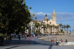 a large building with a clock tower and palm trees at Melia Sitges in Sitges