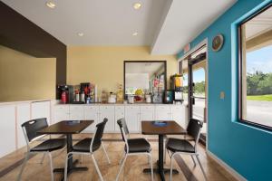 - une cuisine avec deux tables et des chaises dans une pièce dans l'établissement Rose Garden Inn & Suites Thomasville, à Thomasville