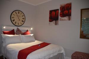 a bedroom with a bed with a clock on the wall at Anni Bos in Stellenbosch