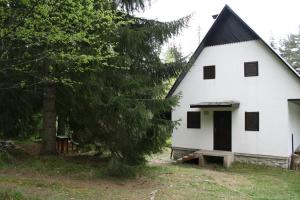 a white house with a black roof and a bench at Chata Čučka in Pribylina
