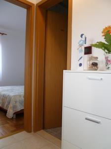 Cette chambre comprend un lit et un réfrigérateur blanc. dans l'établissement Appartamento Camelia, à Fažana