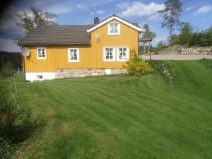 uma casa amarela com um grande quintal em frente em Hagen em Vennesla