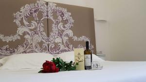 a bottle of wine and a rose on a bed at Easyrome Guest House in Rome