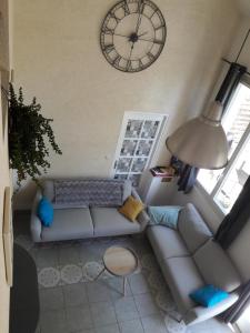 a living room with a couch and a clock on the wall at La Marelle in Avrillé-les-Ponceaux