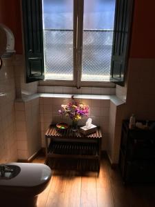uma casa de banho com um vaso de flores sobre uma mesa sob uma janela em Albergue San Lázaro em Sarria