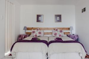 a bedroom with two beds with purple blankets and pillows at At Whale-Phin Guest House in Reebok