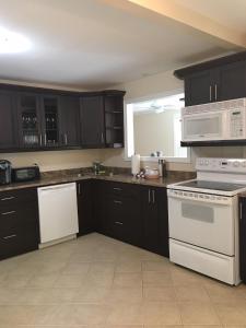 une cuisine avec des armoires noires et des appareils blancs dans l'établissement Victoria Harbour Cottages, à Victoria Harbour