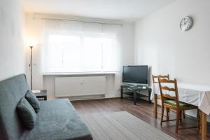 un soggiorno con divano, tavolo e TV di Kaiser Apartments a Offenbach