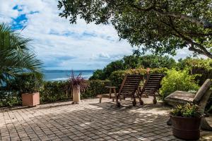 two chairs and a bench sitting on a brick patio at At Whale-Phin Guest House in Reebok