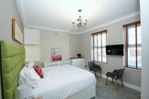 ロンドンにあるブリックレーン ゲストハウスのベッドルーム1室(ベッド1台、椅子2脚、テレビ付)