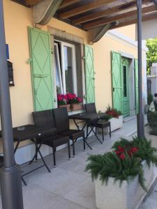 eine Terrasse mit schwarzen Bänken, grünen Türen und Blumen in der Unterkunft Bed and Breakfast Villa Maria in Lovran