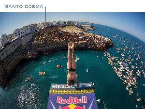 Ein Mann, der von einem Schild im Ozean ins Wasser springt. in der Unterkunft WePuglia - Santo Cosma - La Suite in Polignano a Mare