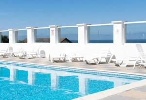 a swimming pool with white chairs and a swimming pool at Surf View House in Newquay