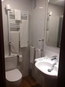 a white bathroom with a toilet and a sink at Hotel Herreros in Castellón de la Plana