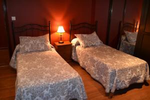 a bedroom with two beds and a lamp on a table at Hostal Pension La Ruta in Paterna del Campo