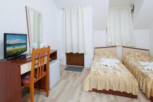 a bedroom with two beds and a desk with a television at Gloria Holiday House in Nesebar