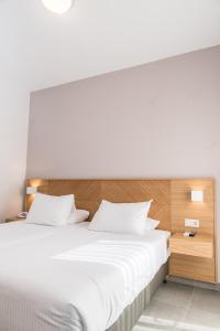 Schlafzimmer mit einem weißen Bett mit einem Kopfteil aus Holz in der Unterkunft Creta Elena in Chania