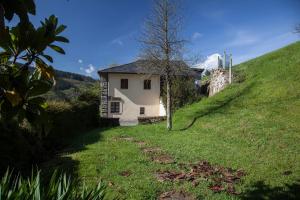 una pequeña casa blanca en una colina con un árbol en Casa de Aldea Vache, en Naraval