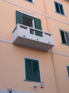a pink building with a balcony with green shutters at Casa Messina Inn in Messina
