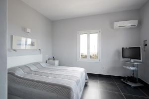 una camera bianca con letto e televisore di Villa Chez Julie a Citèra (Kýthira)
