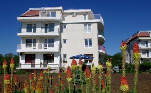 un bâtiment blanc avec des fleurs colorées devant lui dans l'établissement апартамент Веси VeSea, à Nessebar