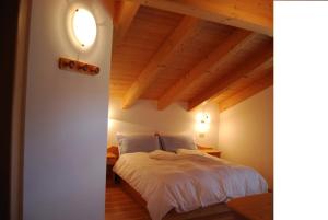 una camera con letto bianco e soffitto in legno di Appartamenti Chalet Orchidea a Canazei