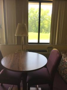 une table, deux chaises et une lampe dans une pièce dans l'établissement Allenwood Motel, à Allentown