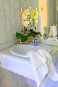 a bathroom sink with a vase of yellow flowers on it at Hotel Escuela Madrid in Madrid