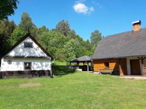 eine Scheune und ein Haus mit einem Rasenhof in der Unterkunft Chaloupka u potoka in Svetla Hora