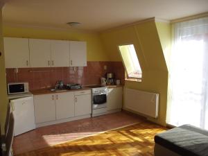 uma pequena cozinha com armários brancos e uma janela em Pillangó Apartman em Hajdúszoboszló