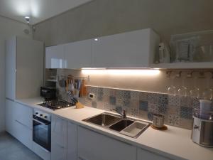 Eine Küche mit weißen Schränken, Spüle und Herd in der Unterkunft WePuglia - Santo Cosma - La Suite in Polignano a Mare + 60 Fotos