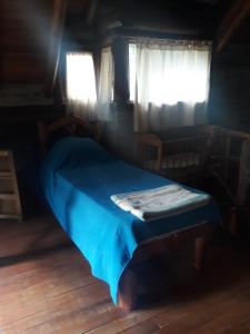 1 dormitorio con 1 cama azul en una habitación con ventanas en Cabaña La Maga en Balneario Mar Azul