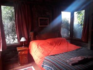 a bedroom with a red bed and two windows at Cabaña La Maga in Mar Azul