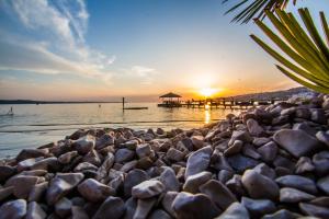a pebble beach with a pier in the water at sunset at Apartment Lucia in Lucija
