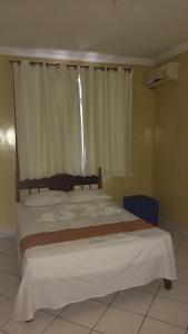 a bedroom with a large bed with a window at Hotel Brasil in Feira de Santana