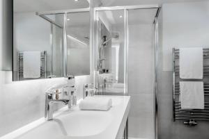 La salle de bains blanche est pourvue d'un lavabo et d'une douche. dans l'établissement Regina's Alpenpanorama, à Sölden